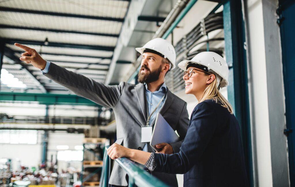 Porträt eines Industriellen und einer Ingenieurin mit Tablet in einer Fabrik bei der Arbeit.
