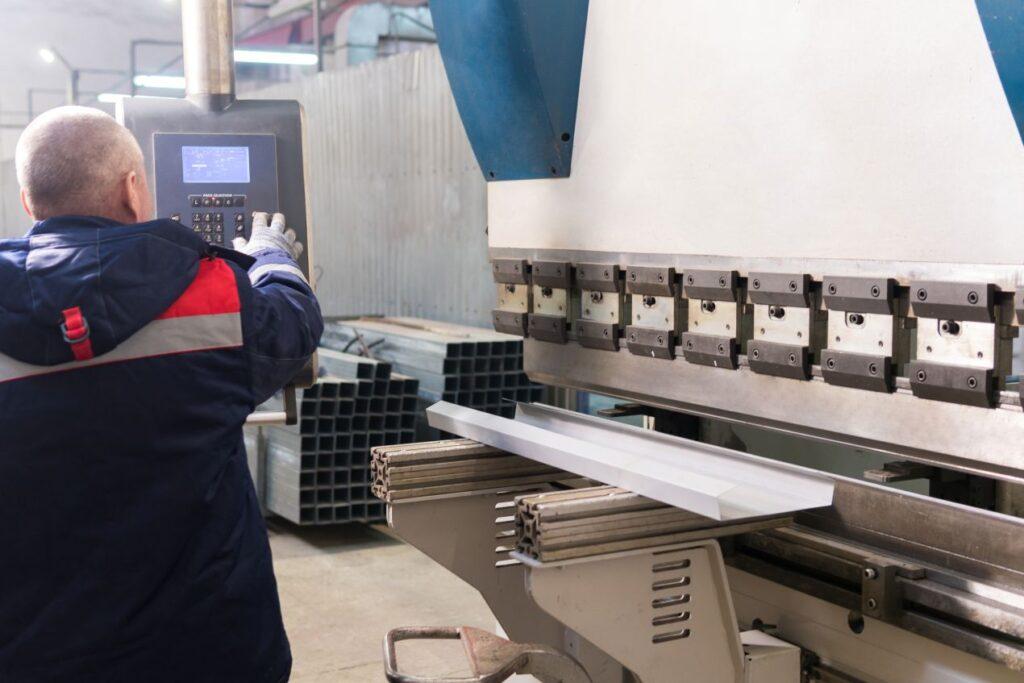 Ein Maschinenbediener steuert eine industrielle Biegemaschine ueber ein digitales Bedienfeld in einer metallverarbeitenden Produktionsumgebung